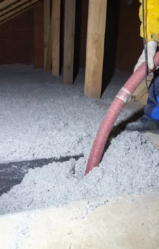 A+ Air Conditioning & Refrigeration technician installing blown-in insulation